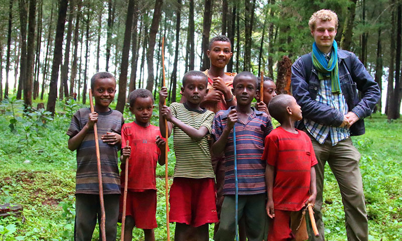 Ein Mann steht neben einer Gruppe afrikanischer Kinder.