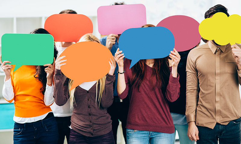 Young people holding up colored speech bubbles